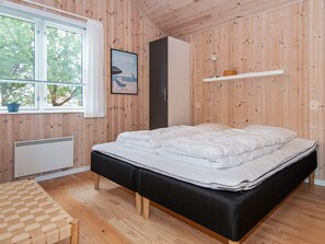 A bedroom with a bed, a radiator, a window with blinds, a poster, and a shelf.