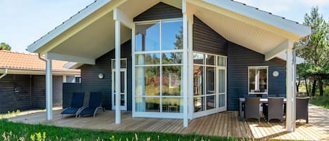 A modern house with a large glass door, a covered patio, and a deck.