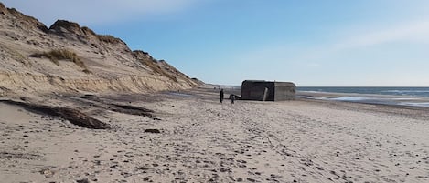 A sandy beach with footprints and a large rock formation.