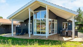 A modern house with a large glass door, a covered patio, and a deck.