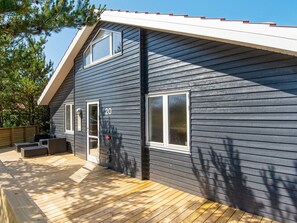 A two-story house with a dark siding exterior, a wooden deck, and a number '20' on the side.
