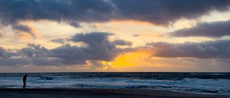 A beach with waves and a sunset.