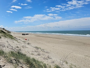 A beach with a dune, a red tent, and a black object on the sand. - 4 Star Holiday Home in Ulfborg (Ulfborg)