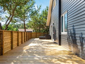 A wooden deck leading to a building with a dark siding exterior.