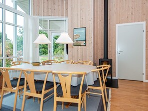 A dining area with a round table, wooden chairs, and a view of greenery outside.