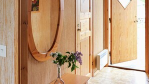 A wooden interior with a large oval mirror, a small table with a vase of flowers, and a door with a window. - 5 Person Holiday Home in Glommen-by Traum (Glommen)