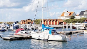 A marina with various boats docked, a sailboat prominently in the foreground, and buildings with red roofs in the background. - 5 Person Holiday Home in Glommen-by Traum (Glommen)