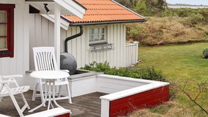 A small house with a red roof, white exterior, and a porch with two white chairs and a table. - 5 Person Holiday Home in Glommen-by Traum (Glommen)