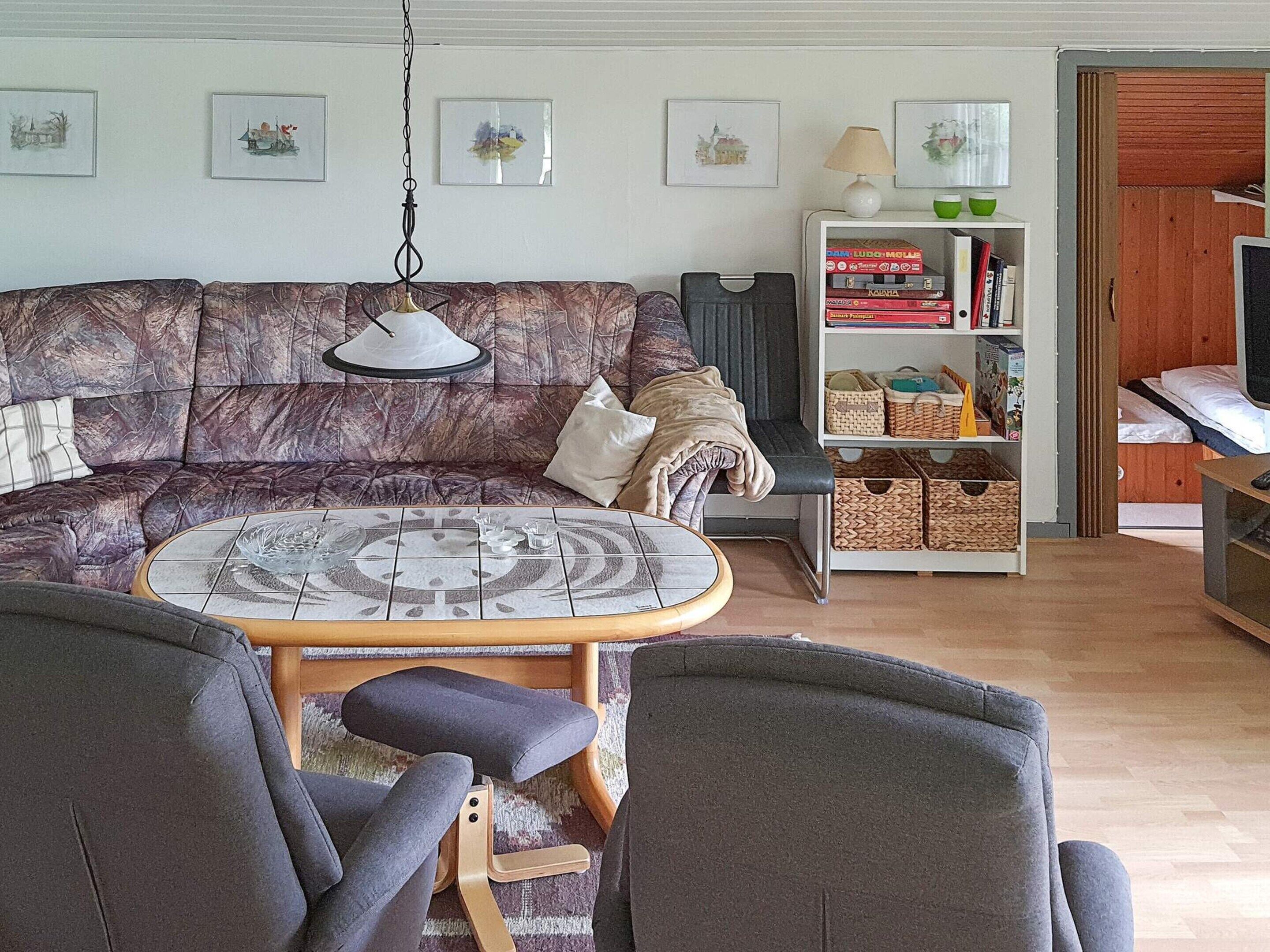 A living room with a patterned sofa, a round coffee table, and a bookshelf.