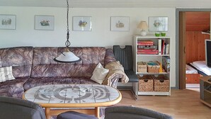 A living room with a patterned sofa, a round coffee table, and a bookshelf. - 6 Person Holiday Home in Sydals (Sydals)