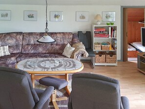 A living room with a patterned sofa, a round coffee table, and a bookshelf. - 6 Person Holiday Home in Sydals (Sydals)