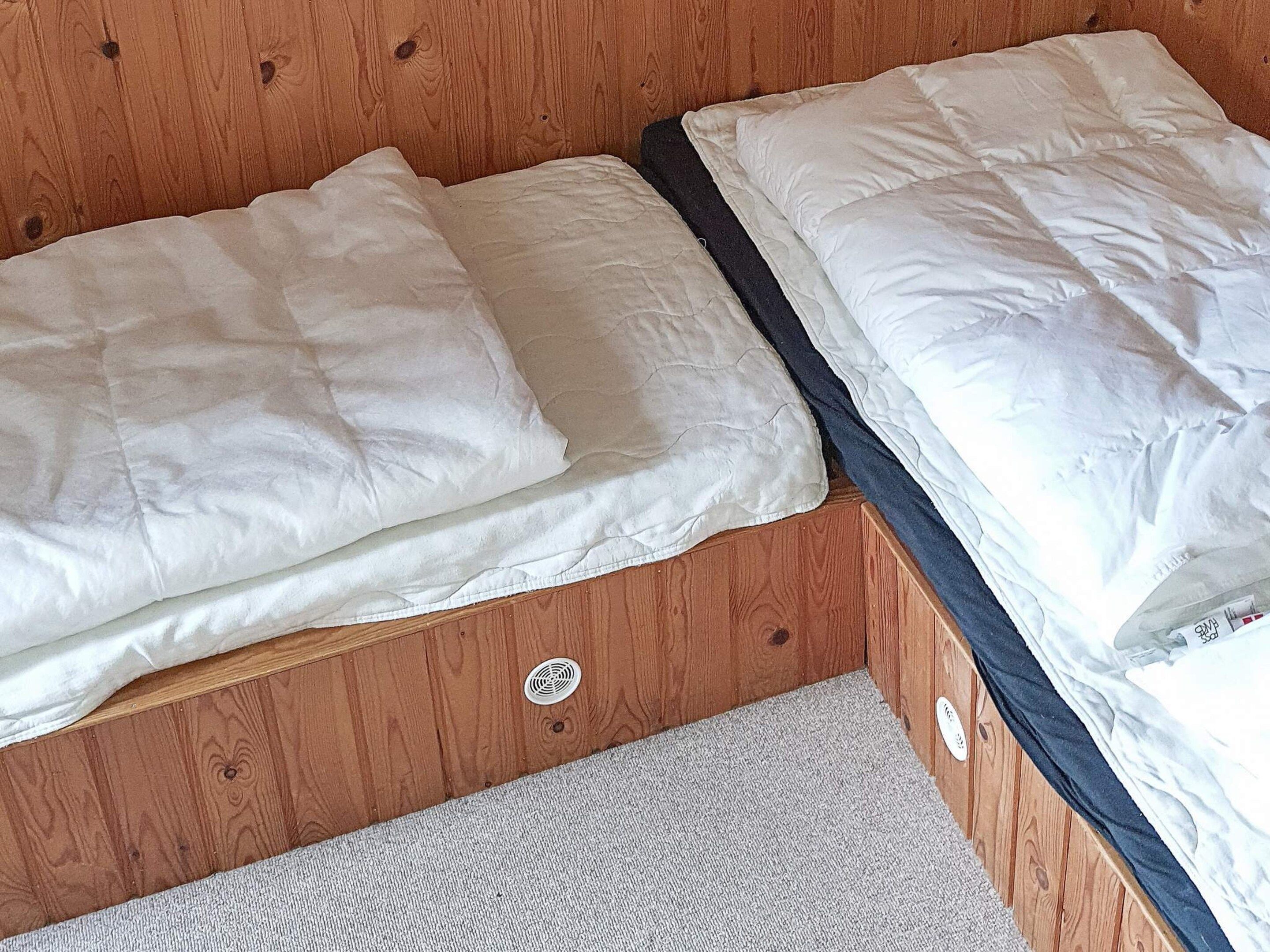 A bunk bed with white bedding and a grey carpeted floor.