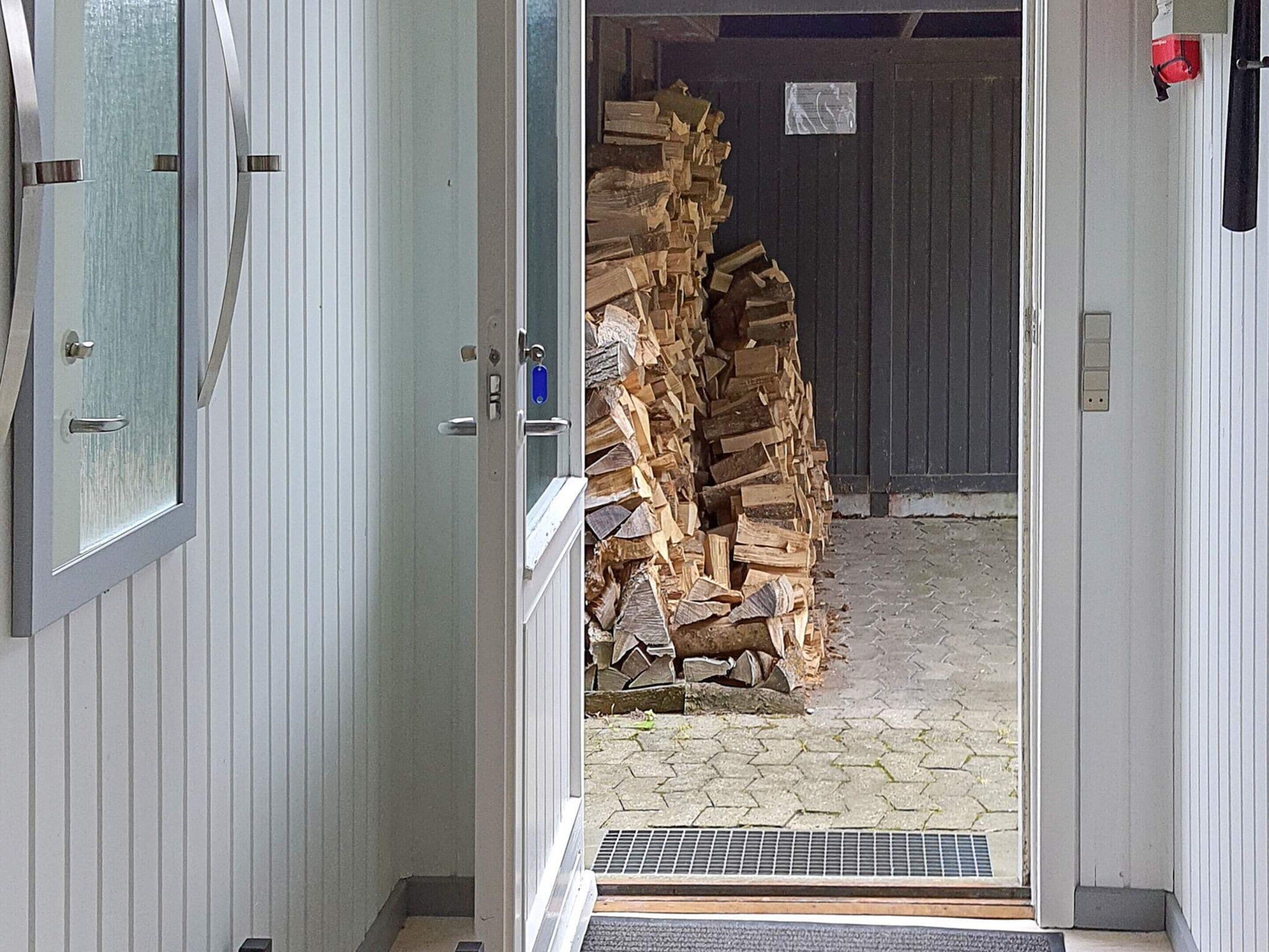 Eine geöffnete Tür, die zu einem Holzstapel führt.