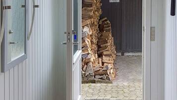 Eine geöffnete Tür, die zu einem Holzstapel führt.