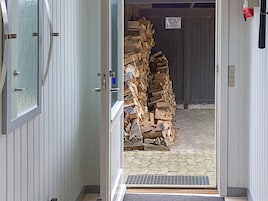 An open door leading to a stack of firewood.