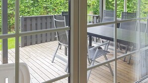 A covered outdoor patio with a table and chairs, surrounded by a wooden deck and a metal railing. - 6 Person Holiday Home in Sydals (Sydals)
