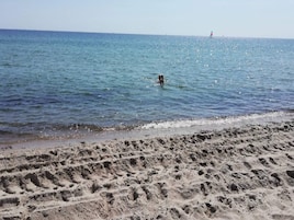 A sandy beach with footprints leading into the water.