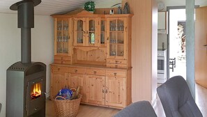 A cozy living room with a wood-burning stove, a wooden cabinet with glass doors, and a grey sofa. - 6 Person Holiday Home in Sydals (Sydals)