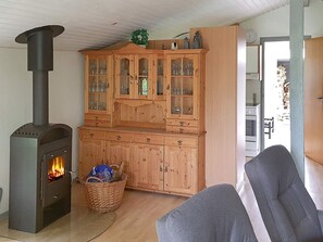 A cozy living room with a wood-burning stove, a wooden cabinet with glass doors, and a grey sofa. - 6 Person Holiday Home in Sydals (Sydals)