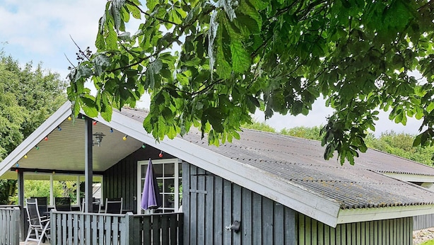A wooden cabin with a porch, a covered seating area, and a window. - 6 Person Holiday Home in Sydals (Sydals)