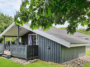 A wooden cabin with a porch, a covered seating area, and a window. - 6 Person Holiday Home in Sydals (Sydals)