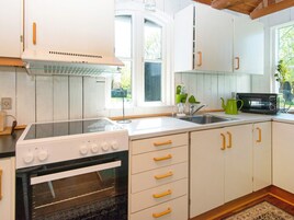 Cocina con armarios blancos, estufa, horno, microondas y ventana que proporciona luz natural.