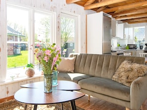 A cozy living room with a sofa, a small table, and a vase of flowers. - 6 Person Holiday Home in Hovborg (Hovborg)