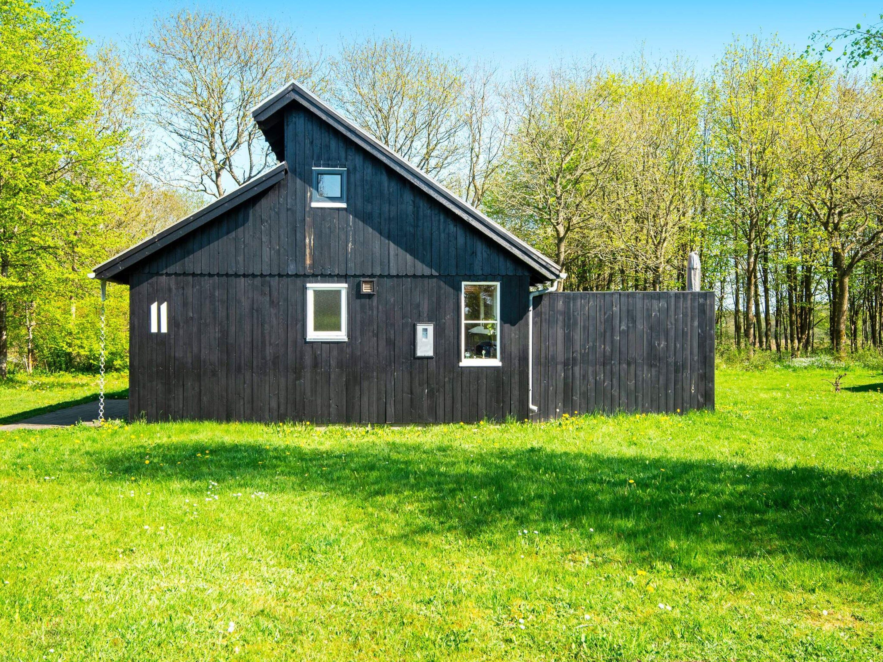 A dark wooden building with a sloped roof, a small window, and a door.