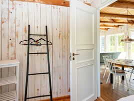 Una habitación con una puerta blanca, una escalera de madera, una mesa de comedor con sillas y una lámpara colgante.