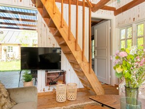 A wooden staircase leading to a room with a flat-screen TV, wicker baskets, and a vase with flowers. - 6 Person Holiday Home in Hovborg (Hovborg)