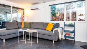 Un salon moderne avec un canapé d’angle gris, une petite table ronde et une étagère décorative.