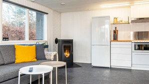 Un salon moderne doté d’une cheminée, d’un canapé, d’une table basse et d’un coin cuisine avec un réfrigérateur et un four.