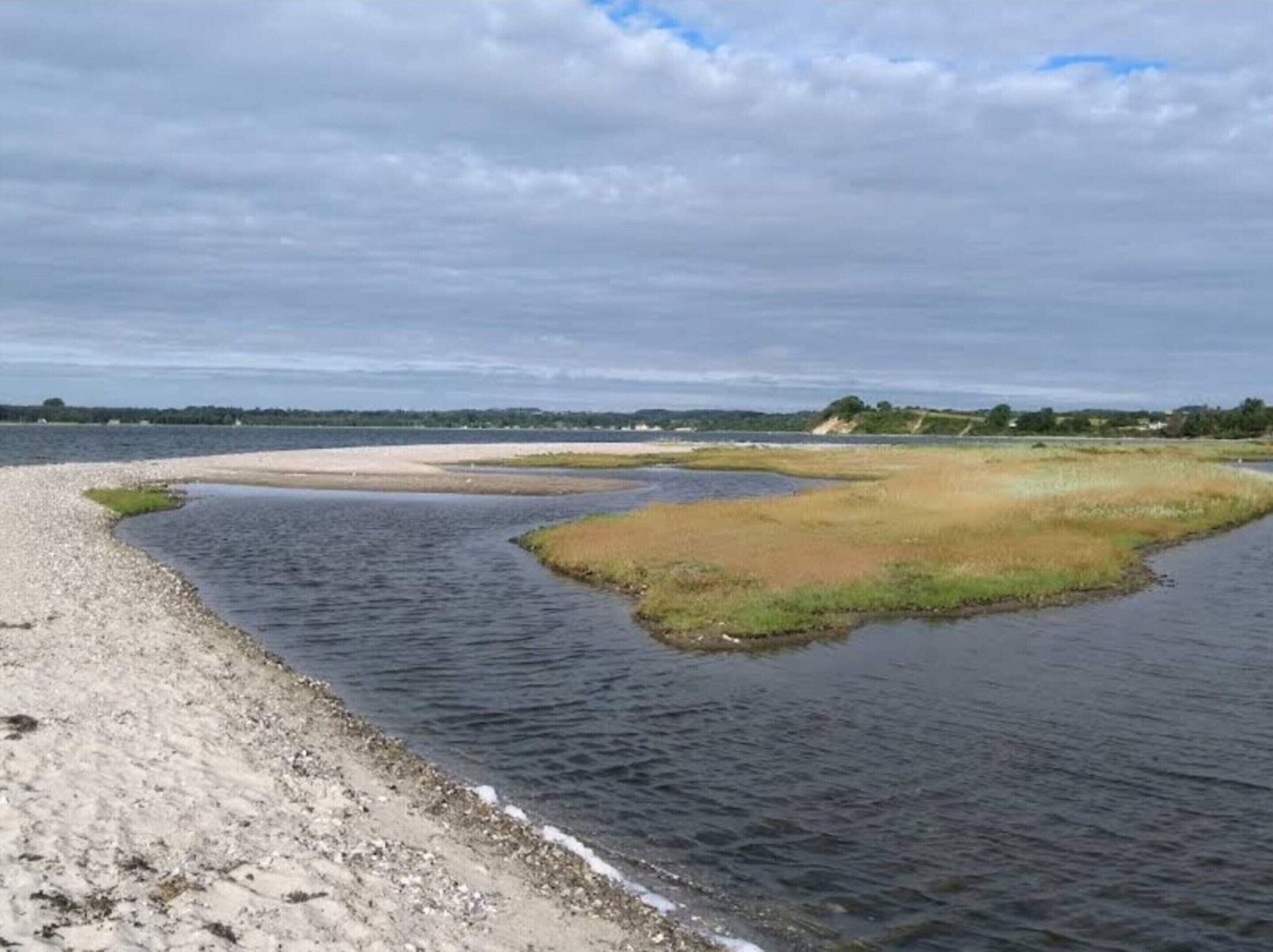 A coastal landscape with a sandy beach and calm water.