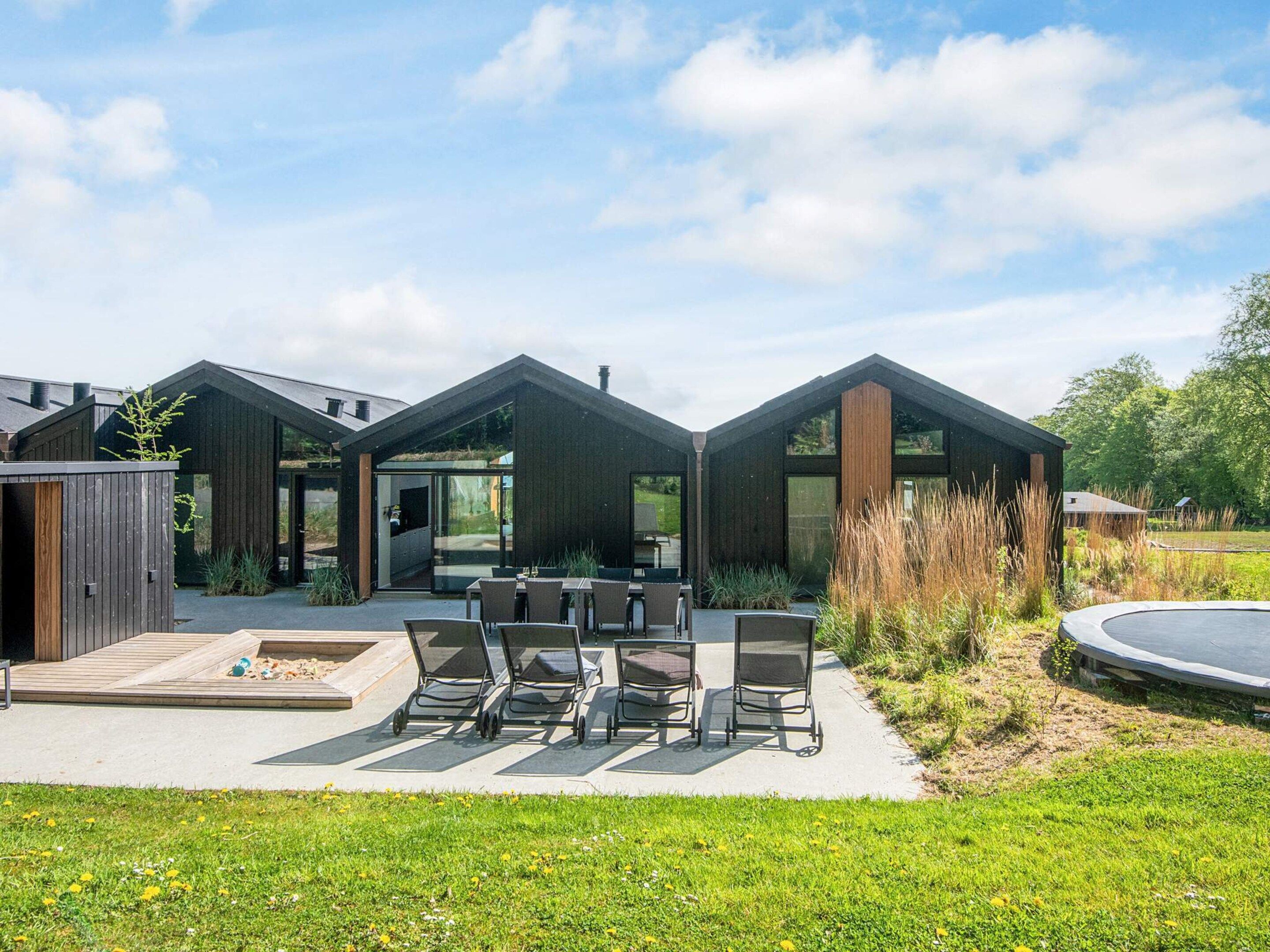 A modern house with a patio area featuring outdoor furniture and a trampoline.