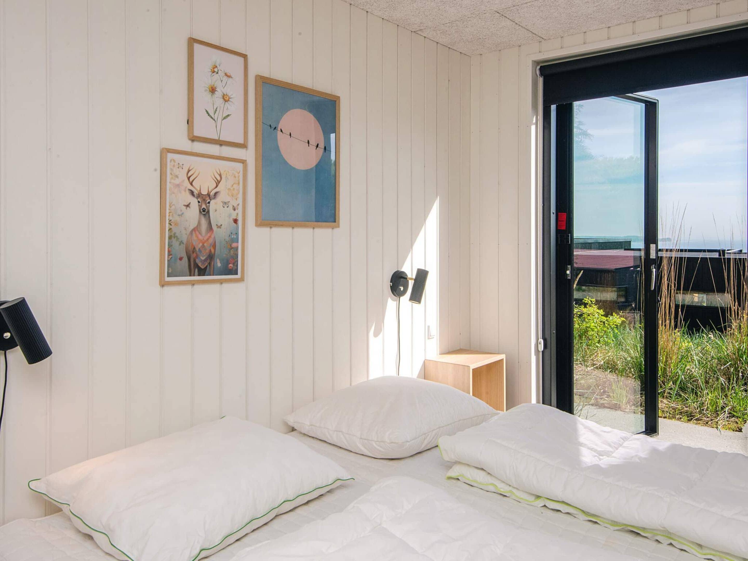 Quarto com duas camas, luminária na parede e quadros decorativos.