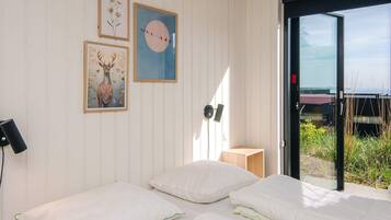 Quarto com duas camas, luminária na parede e quadros decorativos.