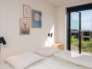A bedroom with two beds, a wall-mounted lamp, and framed artwork. - 5 Star Holiday Home in Sjolund (Sjølund)