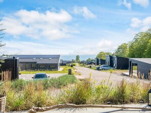 A modern residential area with detached houses, a gravel driveway, and a view of the sea.