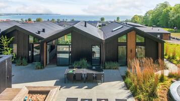 Una casa moderna con patio, mobiliario exterior y vista al mar.