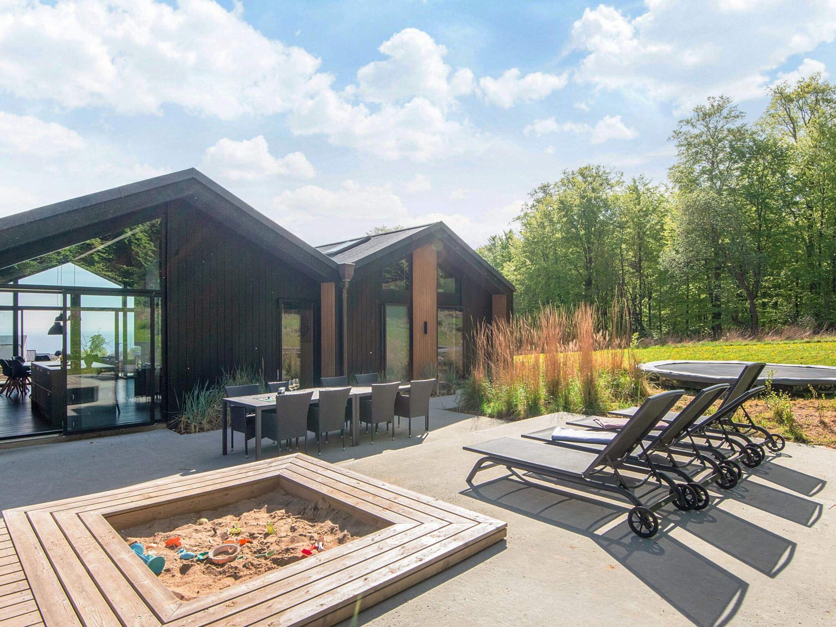 A modern outdoor patio with a fire pit, lounge chairs, and a dining area with tables and chairs.