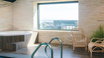Un área de piscina interior moderna con vistas a edificios a través de un ventanal.