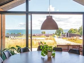Enjoy meals in this dining area with a large round table and comfortable seating, surrounded by a beautiful coastal view.