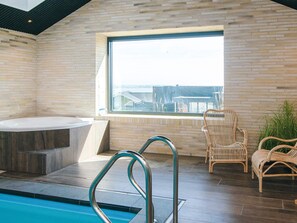 A modern bathroom with a bathtub, a window with a view, and wicker chairs. - 5 Star Holiday Home in Sjolund (Sjølund)