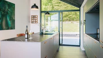 Uma cozinha moderna com uma ilha grande, iluminação pendente e vista para o exterior.