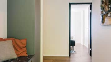 Um corredor com um banco, uma porta que dá para outro quarto e um quadro na parede.