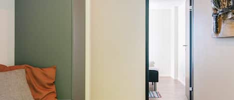 A hallway with a bench, a door leading to another room, and a painting on the wall.