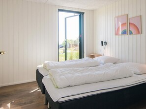 A bedroom with a bed, a window, and a wall-mounted light fixture. - 5 Star Holiday Home in Sjolund (Sjølund)