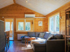A cozy cabin interior with a wooden interior, a gray sofa, a small table, and a window overlooking greenery. - 4 Person Holiday Home in Vesterlanda-by Traum (Västerlanda)