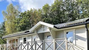 Une maison en bois blanche, dotée d’un balcon et d’un escalier menant à l’entrée.