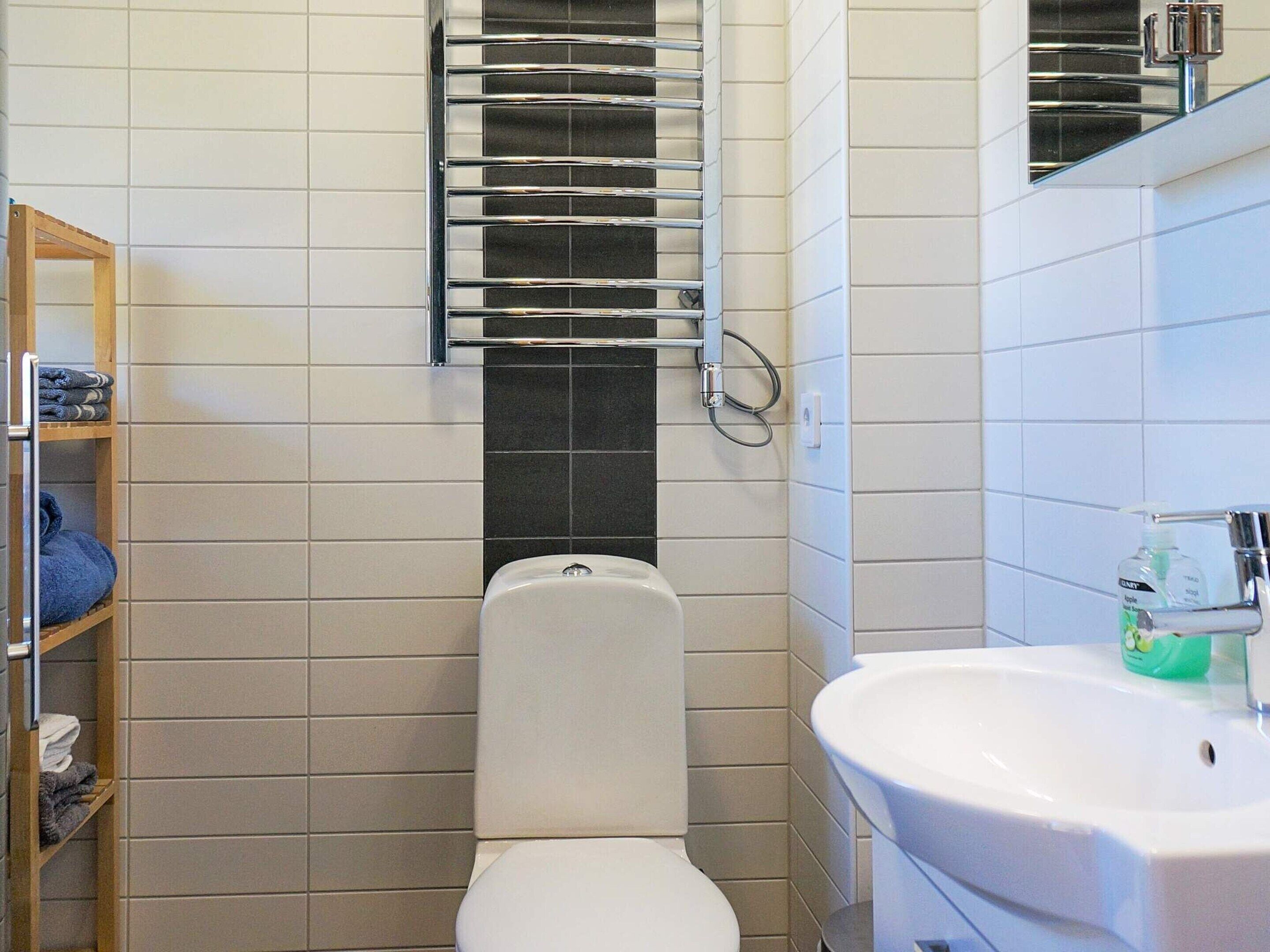 A bathroom with a toilet, a towel rack, and a sink.